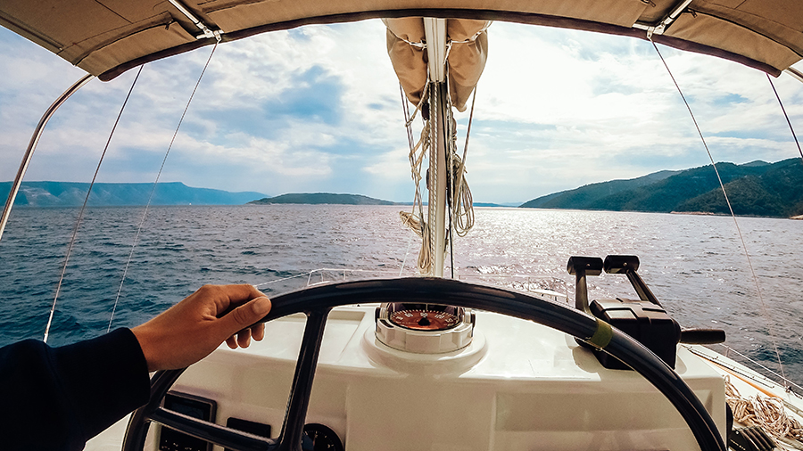 Photo of man holding a boat's wheel illustrates blog: "What Are the Requirements for Boat Insurance in Texas?"