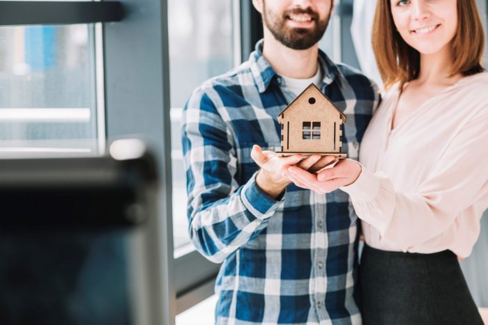 Photo of couple holding small model of a home illustrates blog: "Homeowners Insurance in Texas: What You Need to Know"