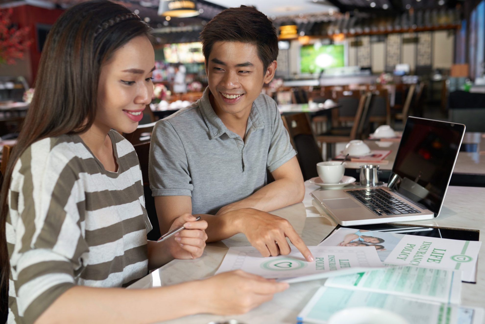 Photo of smiling couple looking at documents illustrates blog: "Term Life Insurance vs. Permanent Insurance"