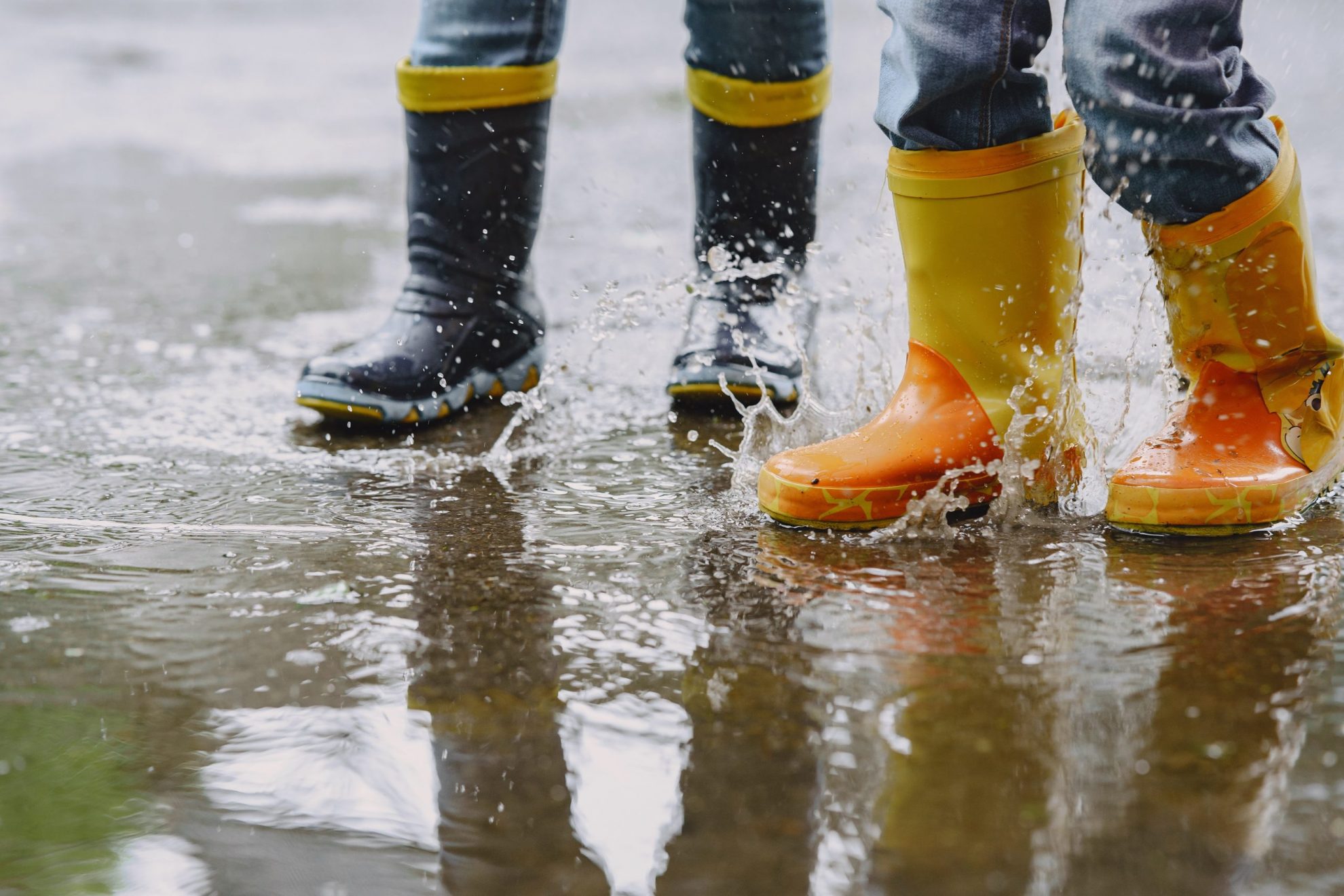 Photo of kids wearing rain boots in puddle illustrates blog:; "Rainy Season Is Here: This Is the Right Time to Get Flood Insurance"