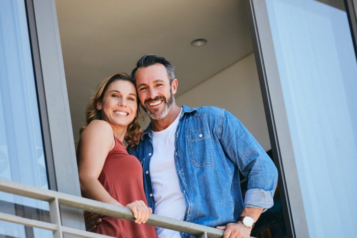 Photo of happy couple in a balcony illustrates blog: "Homeowners Insurance: 6 Extra Coverages You Should Consider"