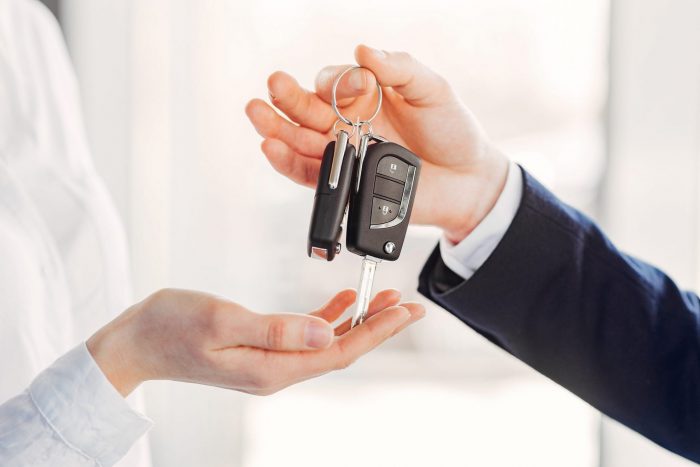 Photo of man handing car keys to woman illustrates blog: "Does Your Credit History Impact Your Auto Insurance Rates in Texas?"
