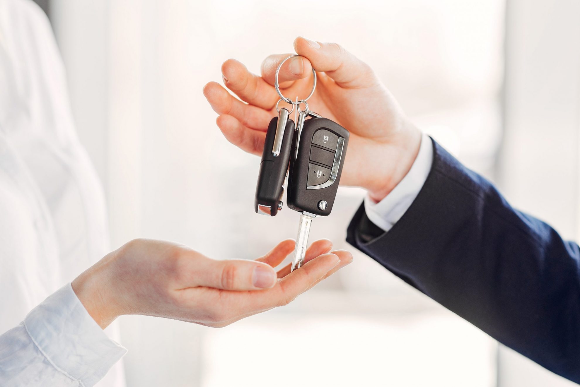 Photo of man handing car keys to woman illustrates blog: "Does Your Credit History Impact Your Auto Insurance Rates in Texas?"