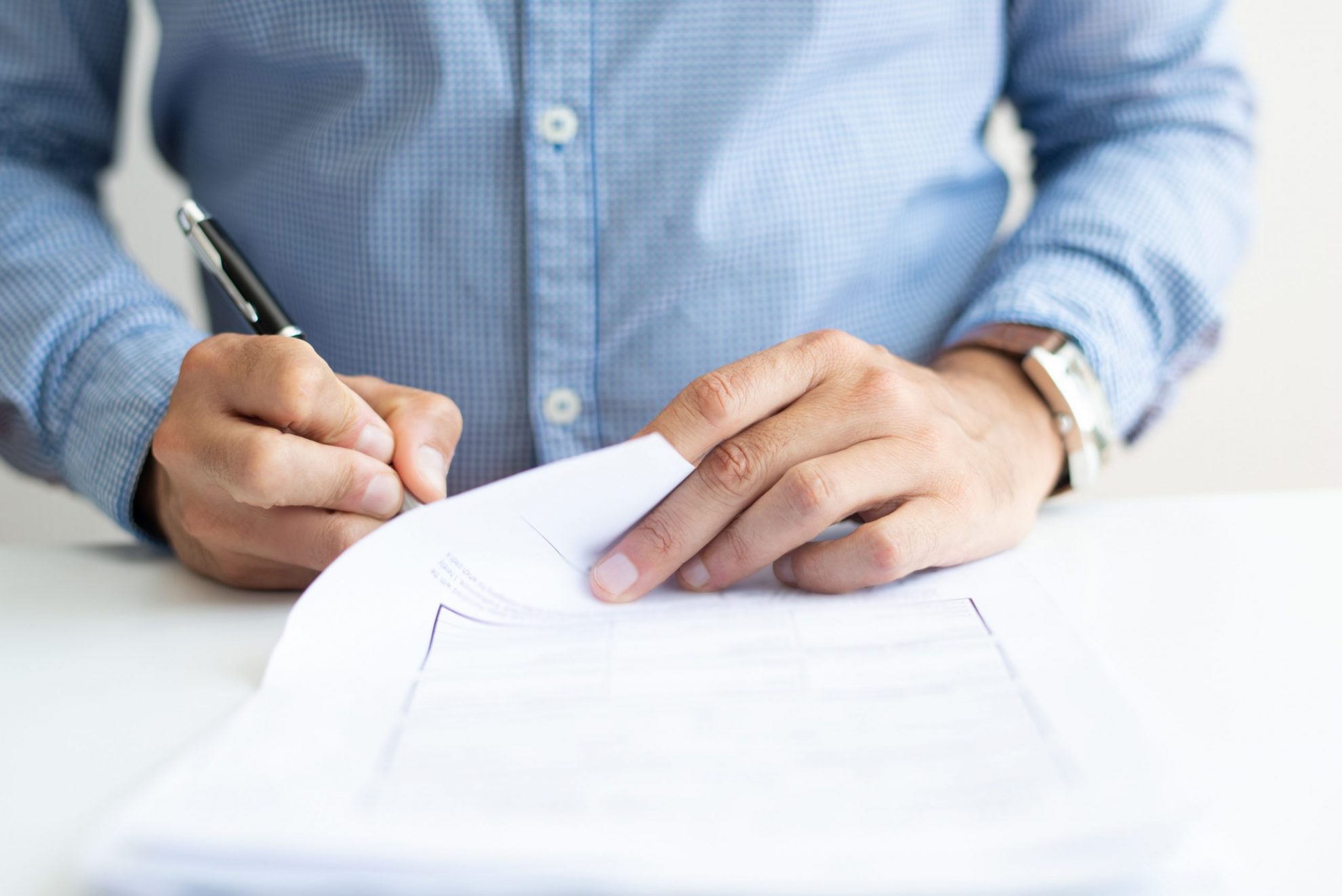 Closeup of man signing sheet of paper illustrates blog: "What Are the Texas Life Insurance Laws?"