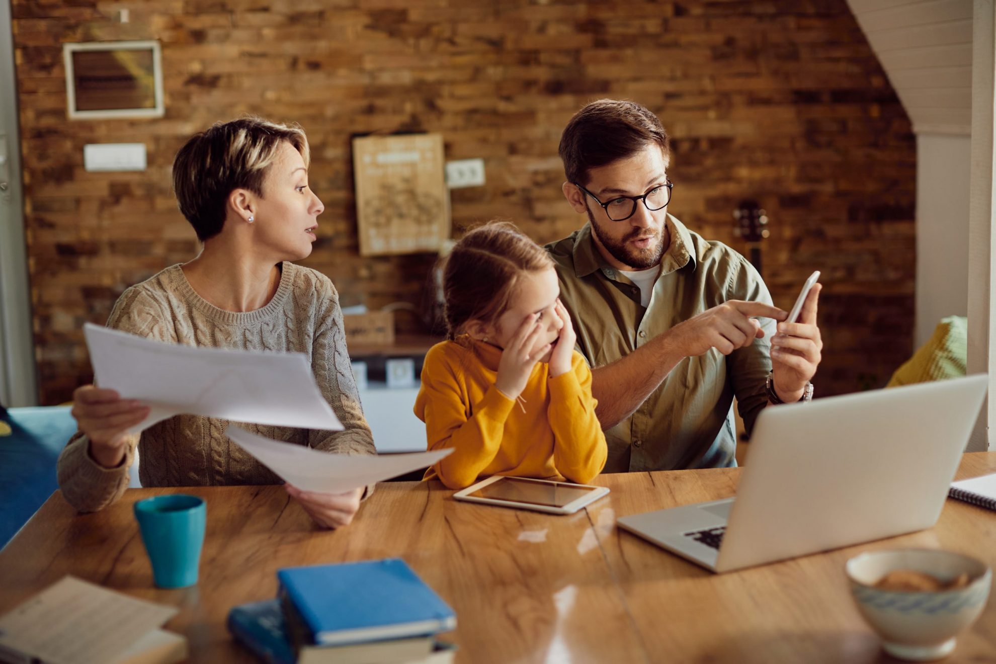 Photo of family looking at smartphone and laptop illustrates blog "Will Insurance Companies Look at My Claims History?"