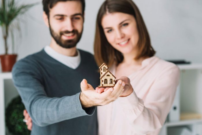 Photo of couple holding tiny toy house illustrates blog: "What Does Flood Insurance Cover in Texas?